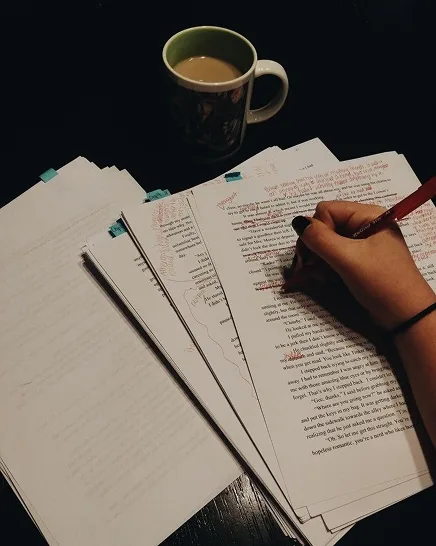 An editor's desk with a manuscript and a red pen